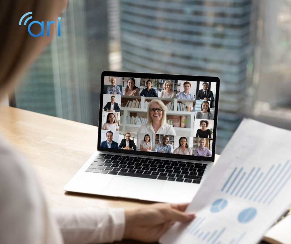 Corporate professional reviewing printed financial charts while participating in a multi participant video conference on a laptop in a modern office setting.