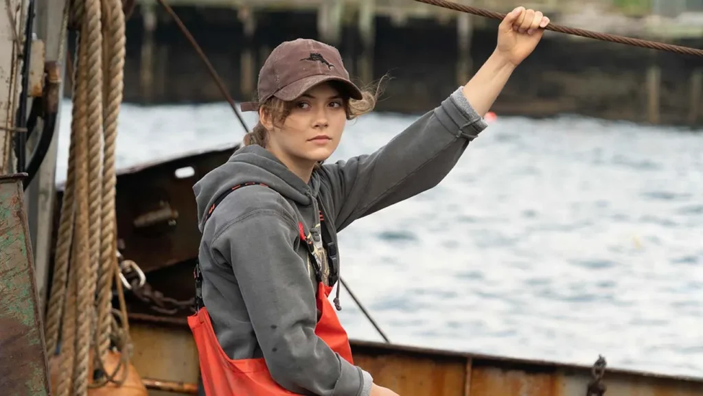 Young woman working on a fishing boat in a scene from the film CODA, a movie exploring Deaf family life and sign language communication.