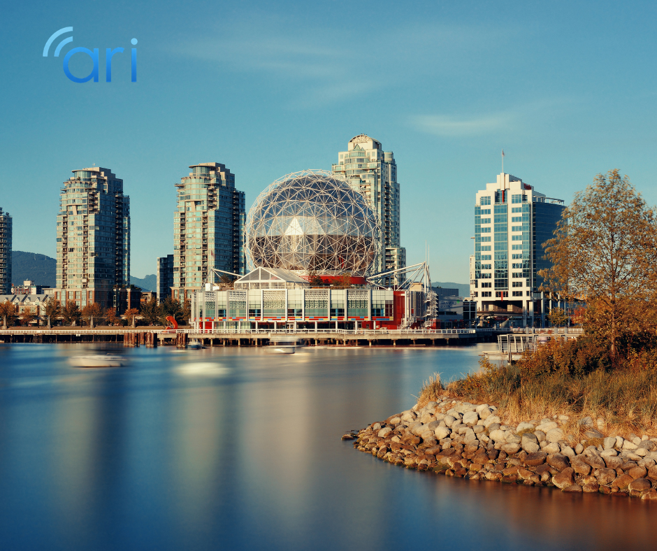 Science World geodesic dome at False Creek in Vancouver surrounded by waterfront buildings and calm water under a clear sky.