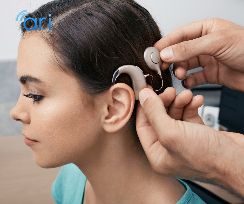 Audiologist placing a behind the ear cochlear hearing aid on a patient during a hearing evaluation appointment.