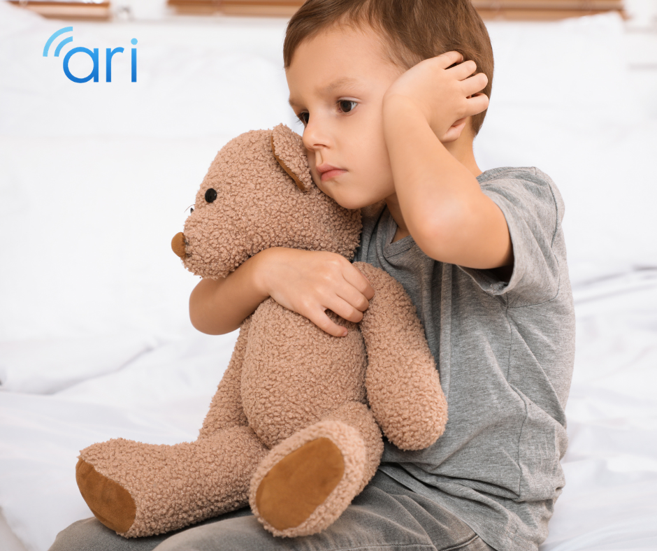 Child wearing a hearing aid while holding a teddy bear, representing hearing loss in early childhood and the need for inclusive support and communication access.